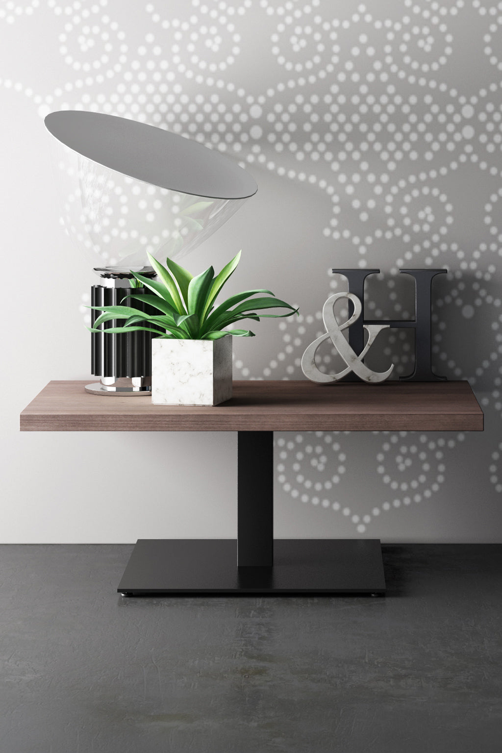 La Table basse Coffee Pop - H40 cm de Monsieur Bureau, caractérisée par un socle noir et une fabrication italienne, présente une plante en pot, une lampe transparente, une bougie noire et blanche, et les lettres métalliques H & sur un mur gris à pois blancs.