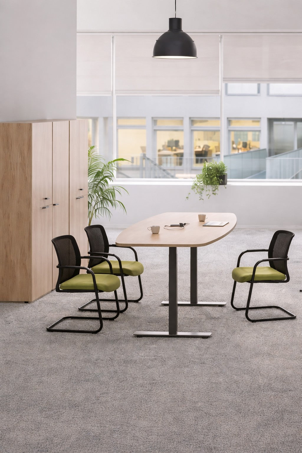 Un espace de réunion moderne comprend la table Monsieur Bureau Table tonneau électrique Top & Down (6/8 personnes), quatre chaises noires avec des coussins verts, des tasses à café, un bloc-notes, des plantes en pot, des armoires, de la moquette et de grandes fenêtres pour la lumière naturelle..#combo_chene_nebraska_noir