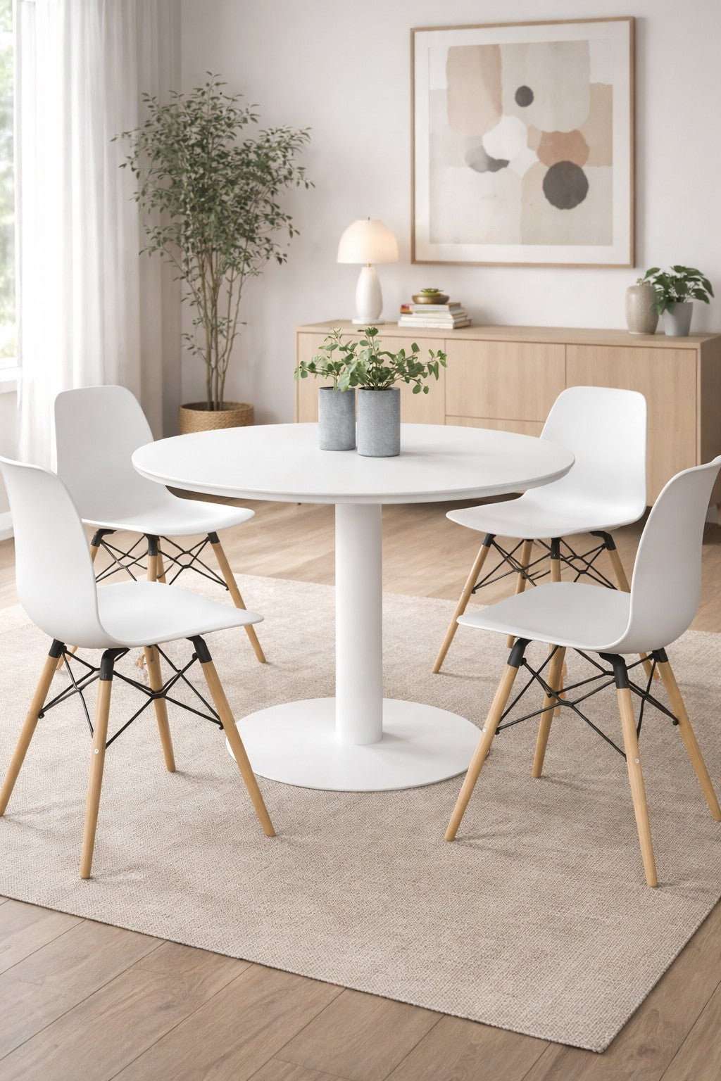 A Monsieur Bureau Table de Collectivité Ronde Tempo au plateau stratifié blanc, accompagnée de quatre chaises blanches à pieds en bois, est placée sur un tapis dans une pièce lumineuse.#combo_blanc_blanc