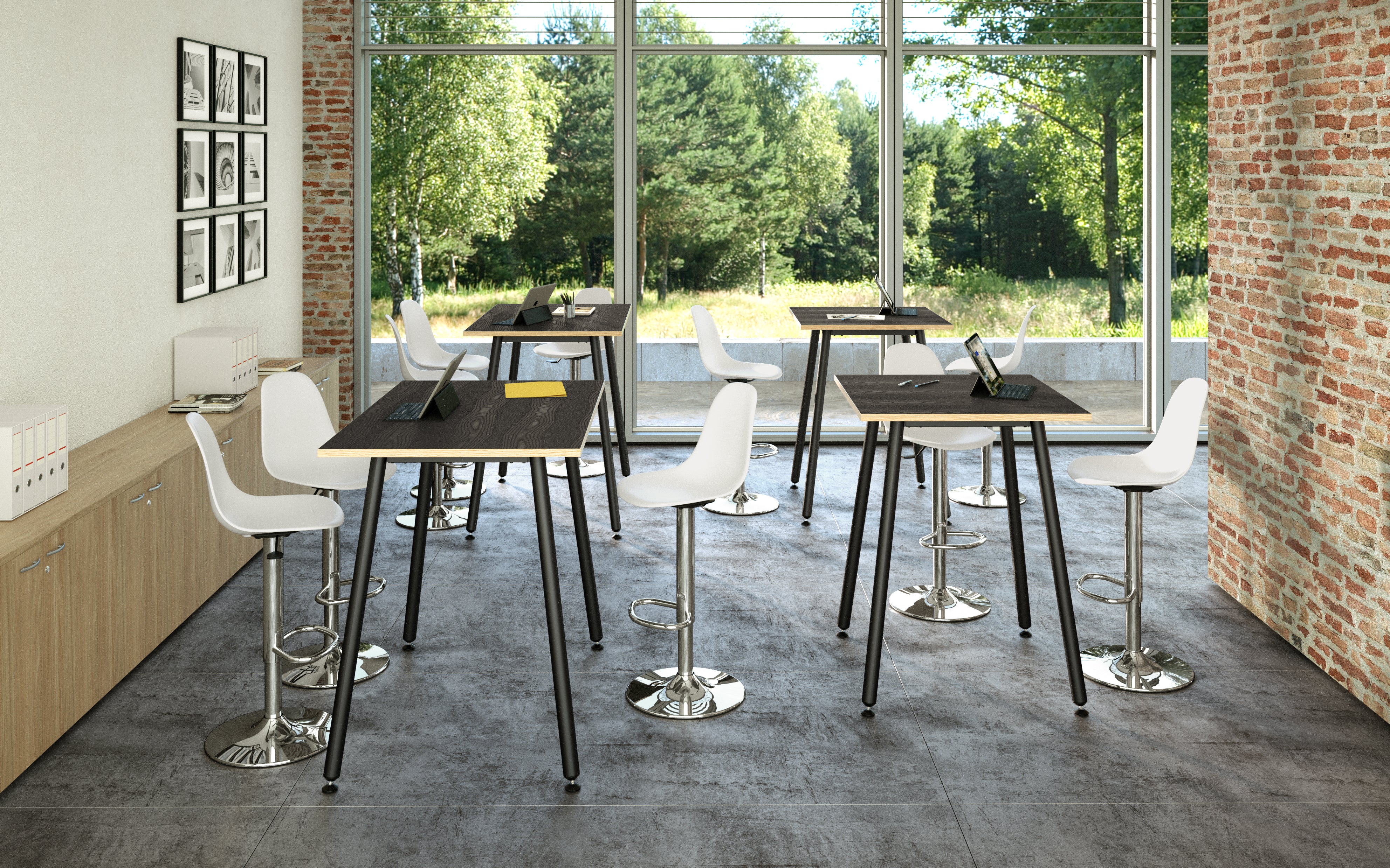 Salle de classe moderne avec table haute design industriel Nature Métal de Monsieur Bureau et tabourets de bar blancs, grandes fenêtres avec vue sur la verdure, murs en briques, sol en pierre - idéal pour les espaces collaboratifs avec tablettes et cahiers sur les tables.