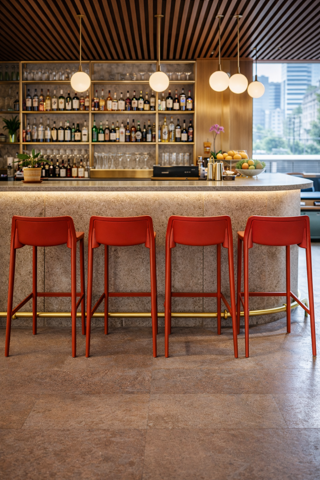 Dans un bar moderne, quatre Tabouret Haut Leus en Polypropylène Anti-UV by Monsieur Bureau sont alignés sur un comptoir en marbre, avec des étagères de bouteilles, des lampes globe suspendues et de grandes fenêtres affichant des bâtiments urbains en arrière-plan.